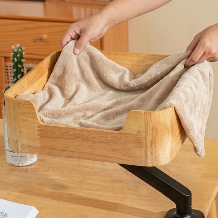 Hands laying a soft beige blanket into the Catomi desk cat bed