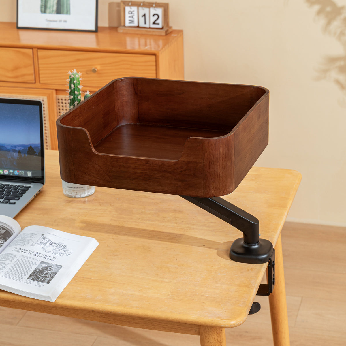 Empty Catomi desk cat bed in Walnut without cushion, clamped to a wooden desk next to a laptop
